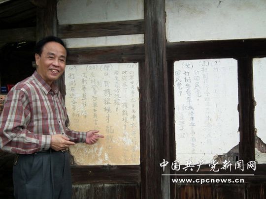 福建省党史研究室原副主任、研究员林强在石峰村瓦窑头厝解读北上抗日先遣队留下的红军标语（罗联久 管其乾摄影）